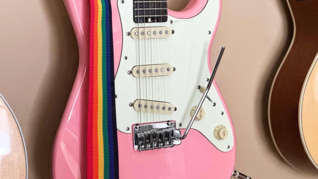 Jason's pink guitar with a rainbow guitar strap and the whammy bar attached